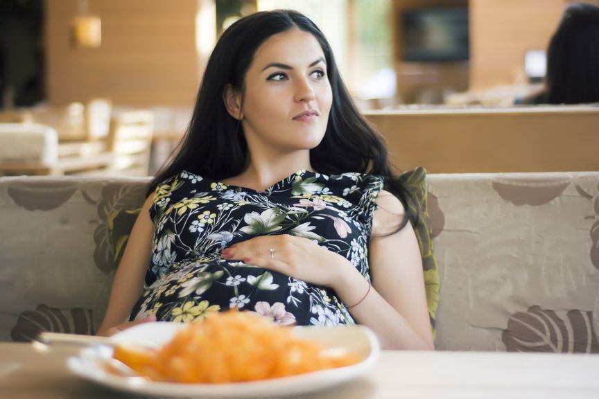 Schwangere hält sich den Bauch nach dem Essen