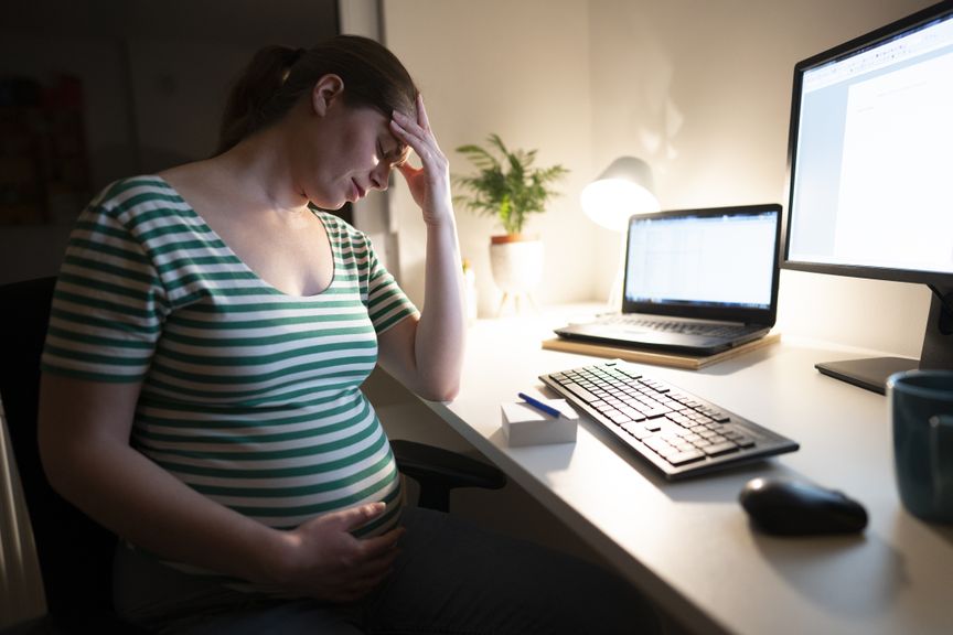 Müde Schwangere abends vor dem Computer