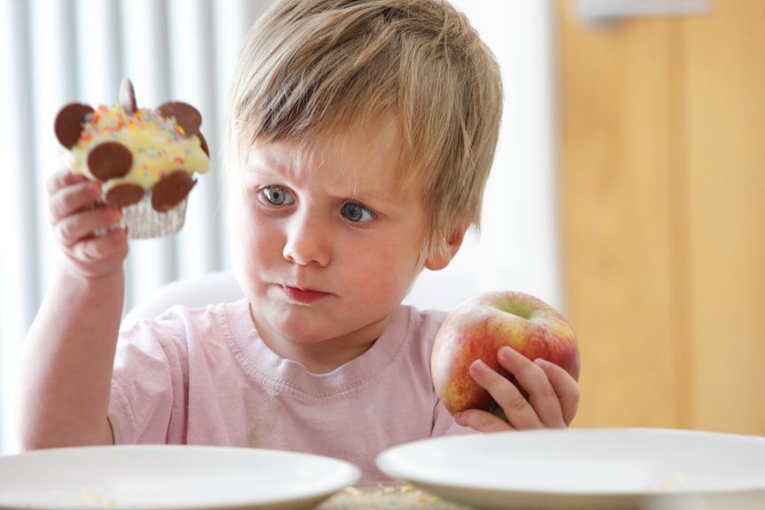 Junge muss zwischen Cupcake und Apfel wählen