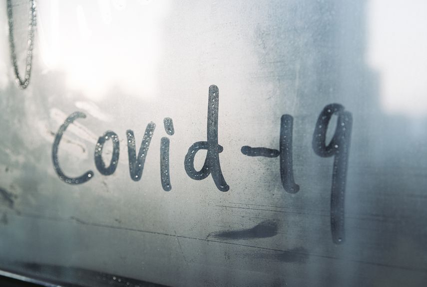 COVID-19 mit Finger auf beschlagene Scheibe geschrieben