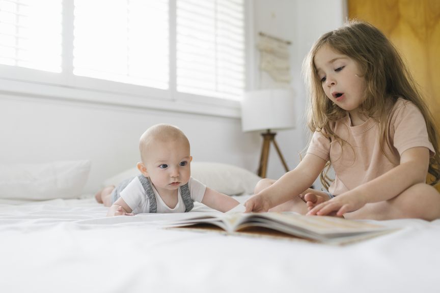 Mädchen liest ihrem Geschwisterchen vor