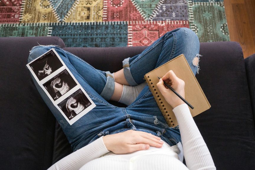 Frau mit Ultraschallbild von ihrem Baby macht Notizen