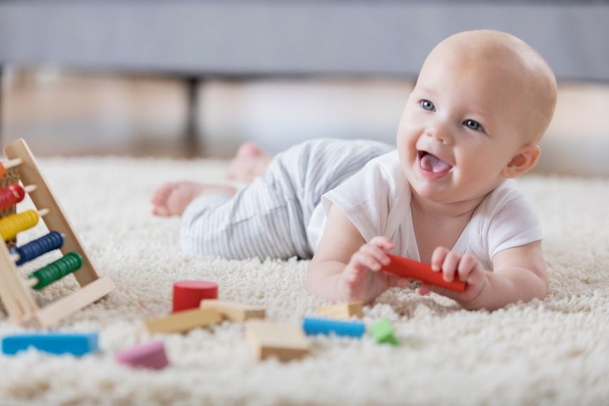 Baby liegt auf dem Bauch, spielt und lächelt