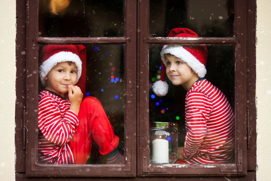 Kinder mit Nikolausmützen sitzen am Fenster