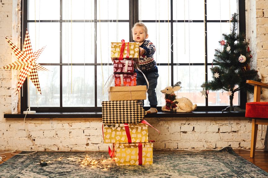 Kleines Kind mit Stapel Geschenken an Weihnachten