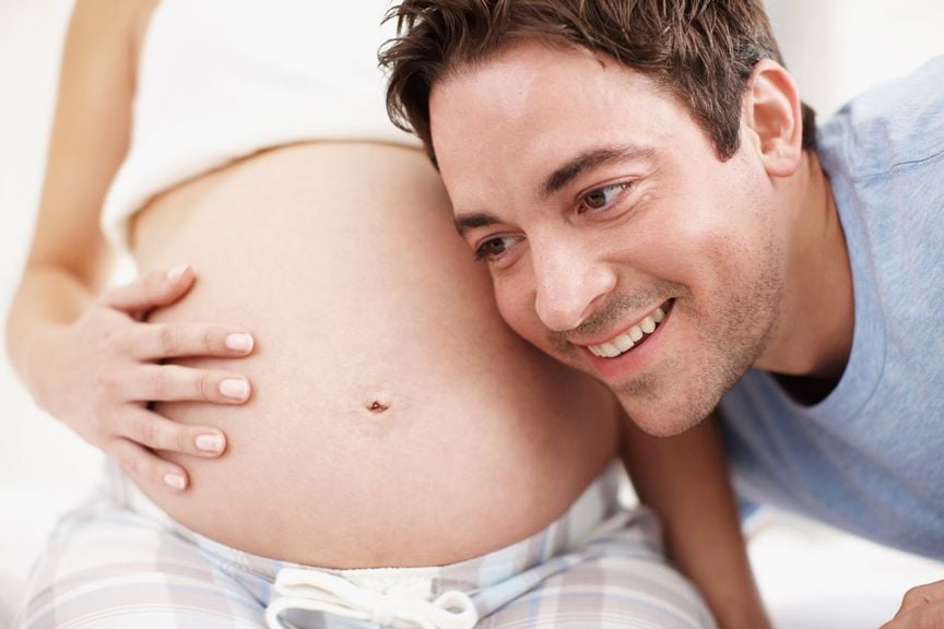 Werdender Vater hält sein Ohr an den Bauch der Schwangeren