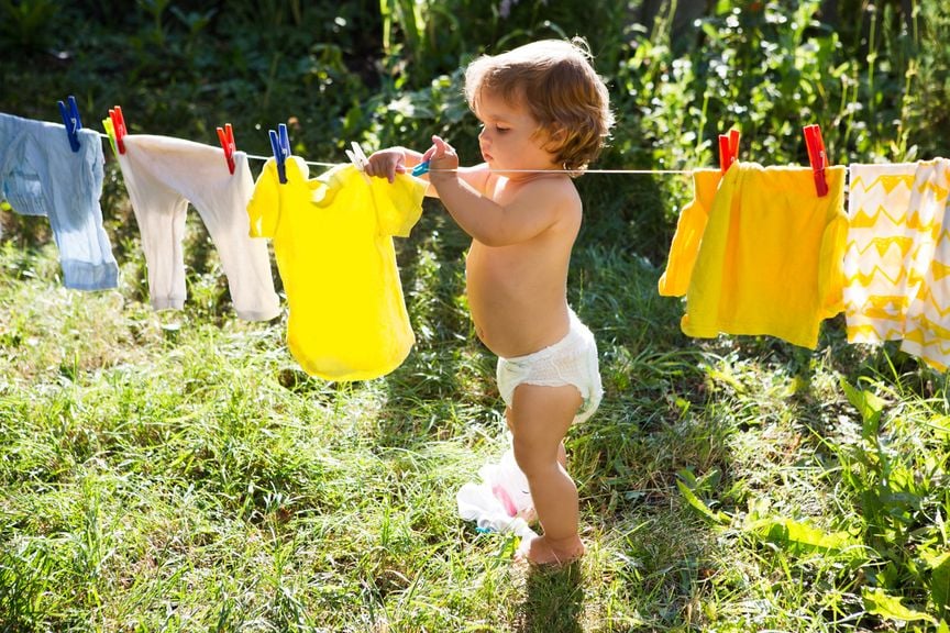 Kind hängt im Garten Kinderwäsche auf die Leine