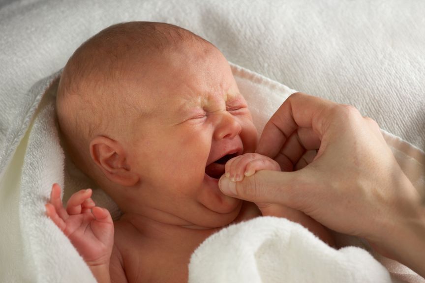 Schreiender Säugling hält Mutters Finger