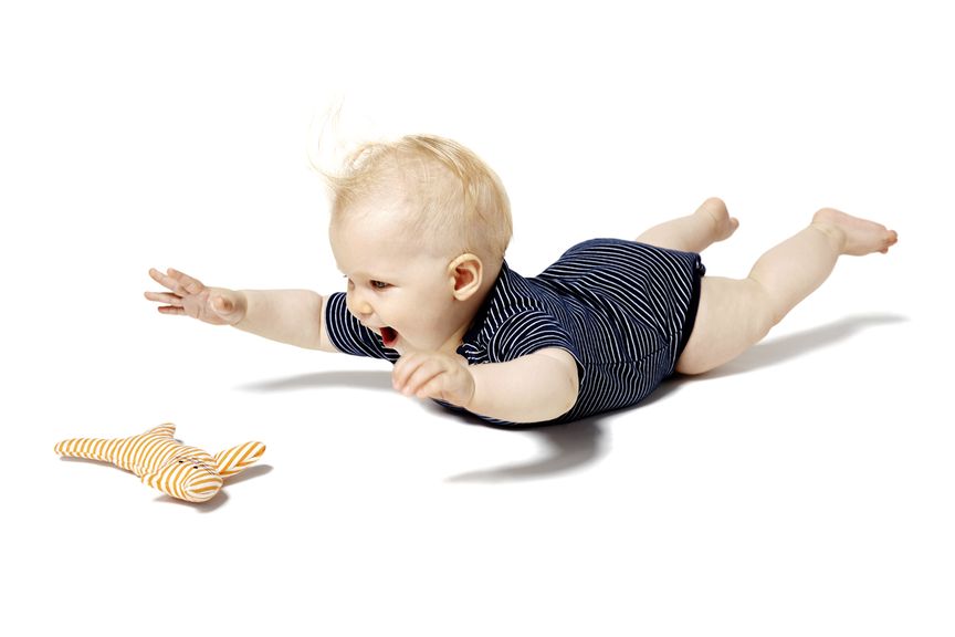 Baby liegt auf dem Bauch, streckt Hände und Beine in die Luft