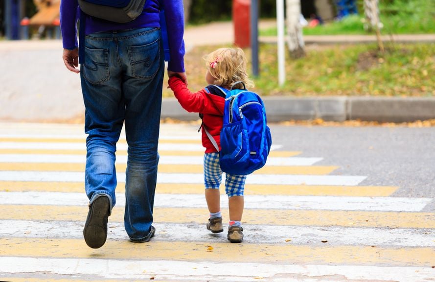 Vater geht mit Kind über den Fussgängerstreifen