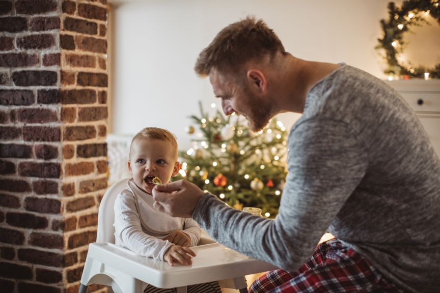 Vater füttert sein Baby an Weihnachten mit Brei
