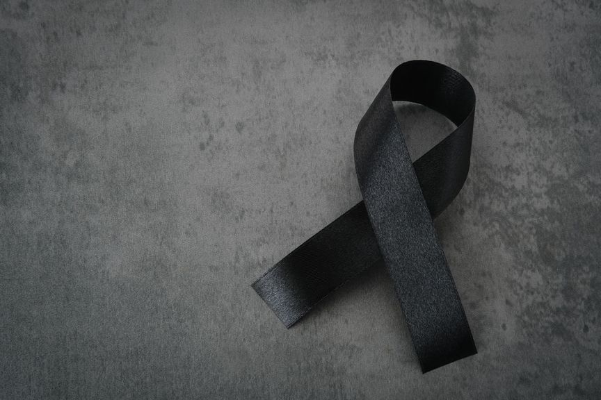 Schwarze Trauerschleife vor dunkelgrauem Hintergrund