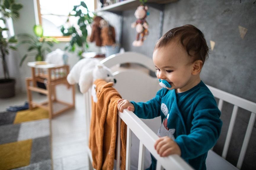 Baby steht im Gitterbett