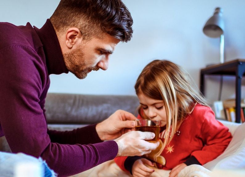 Vater gibt seiner kranken Tochter zu trinken