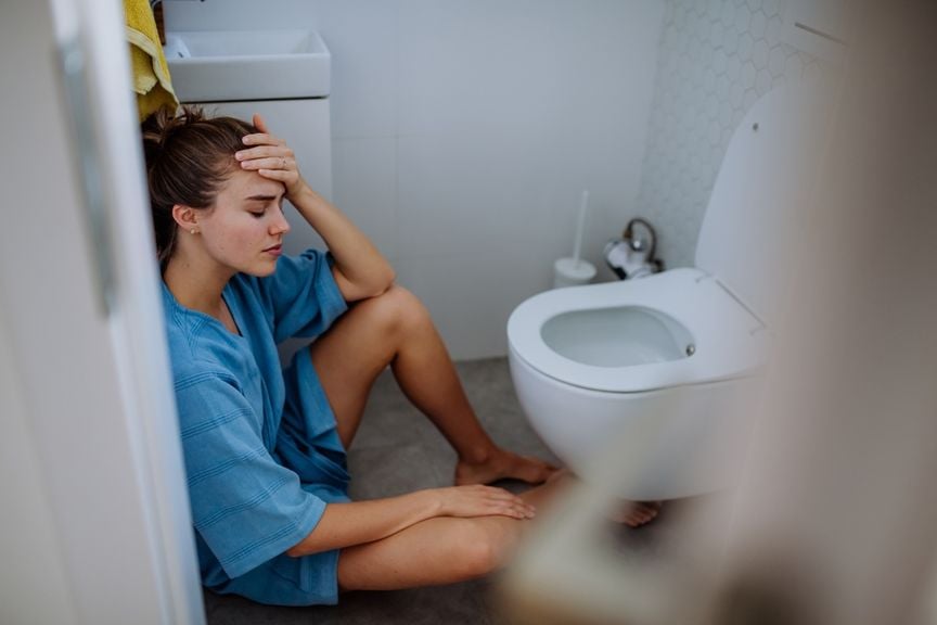 Frau sitzt vor dem WC