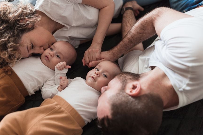 Eltern von Zwillingen halten sich an den Händen und küssen ihre Babys