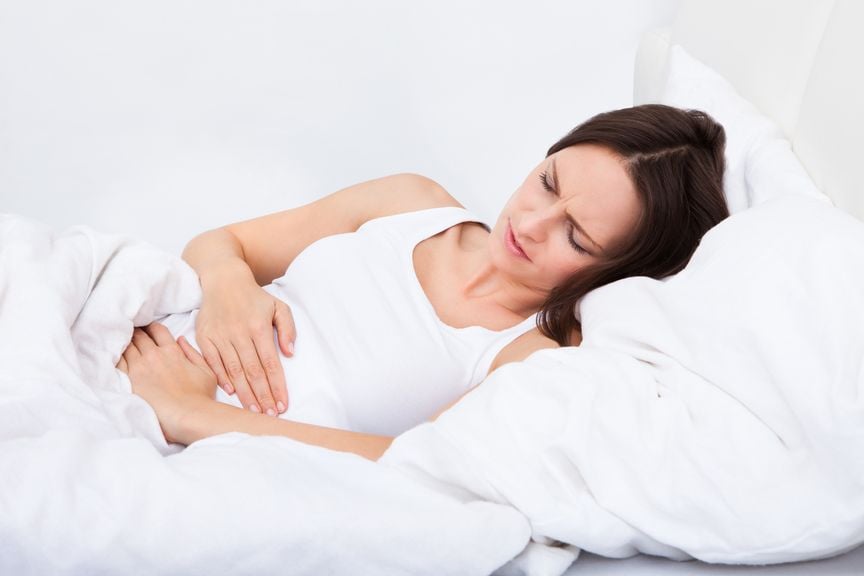 Frau mit Bauchschmerzen im Bett