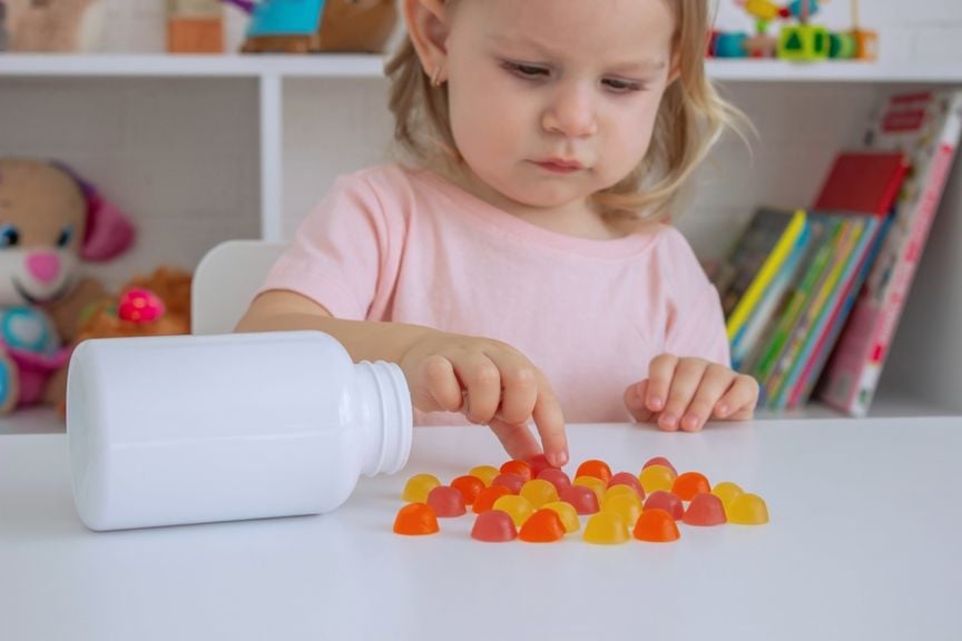 Kind mit einer ausgeleerten Packung Vitamin-Kaubonbons