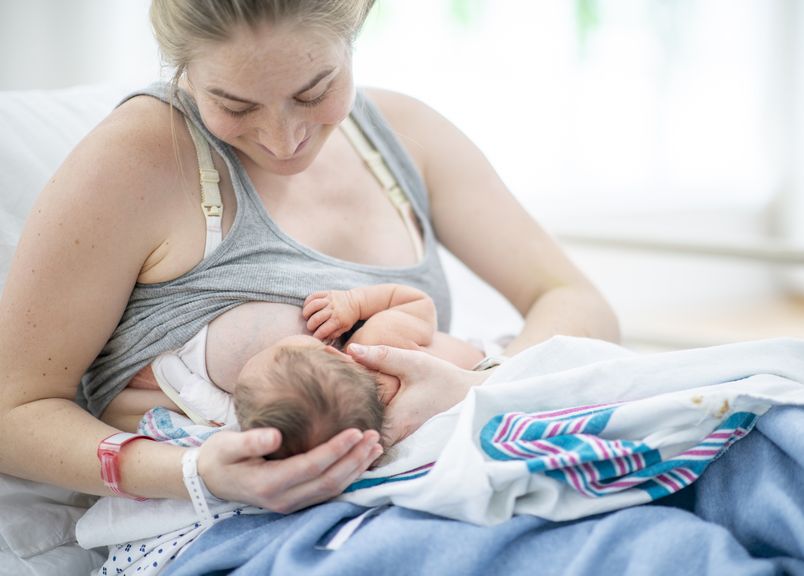 Mutter stillt ihr Neugeborenes im Spital