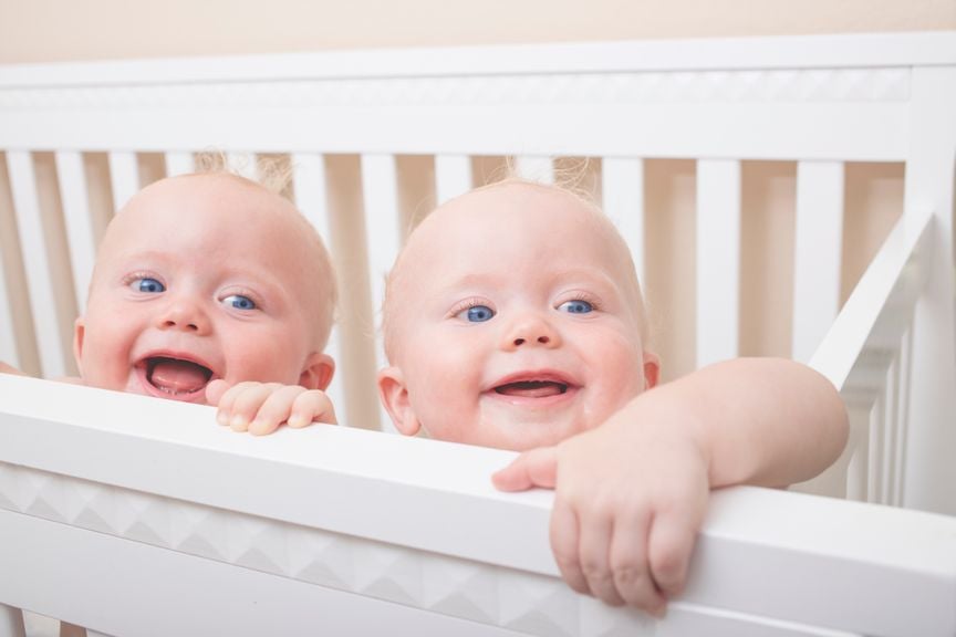 Zwillinge lachend im Kinderbett