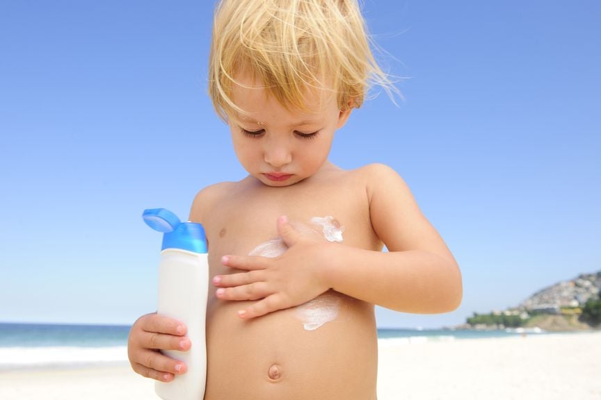 Kind cremt sich mit Sonnenmilch ein,Kind im Sommer schützt sich mit Sonnencreme