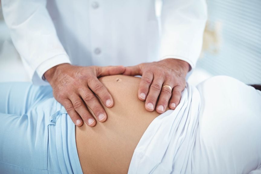 Arzt untersucht den Bauch einer Schwangeren