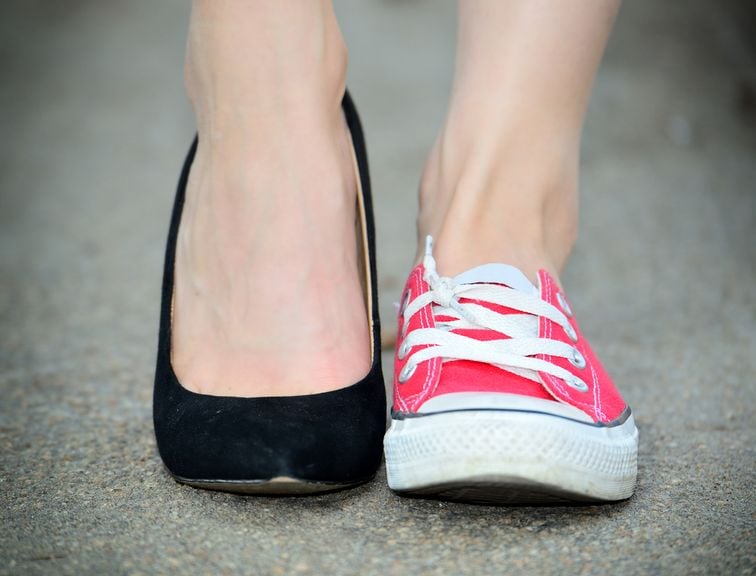Frauenfüsse mit zwei verschiedenen Schuhen