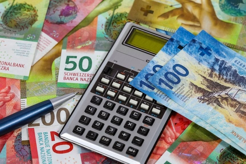 Schweizer Banknoten mit Taschenrechner und Kugelschreiber