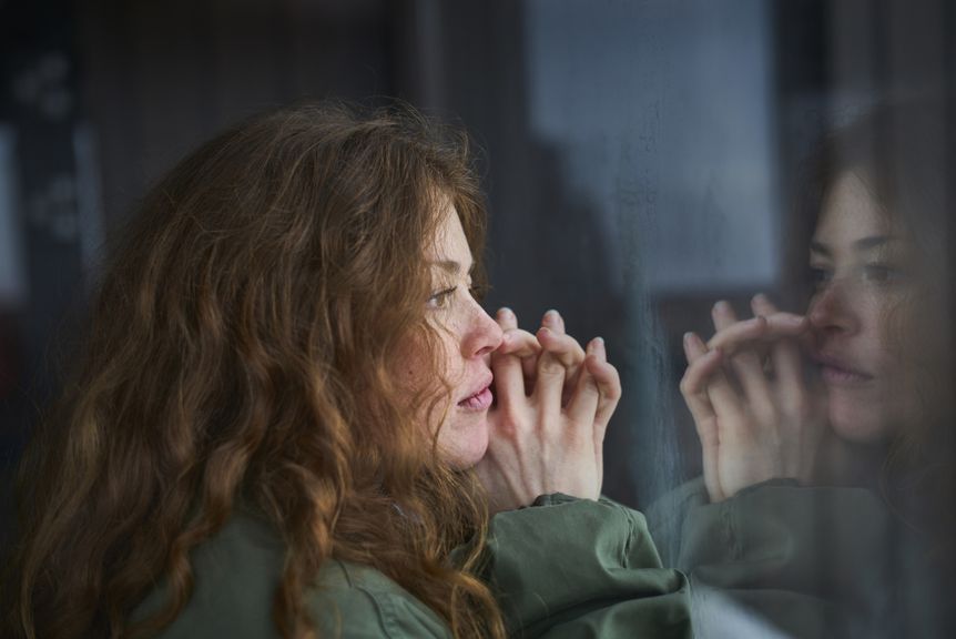 Frau blickt melancholisch aus dem Fenster