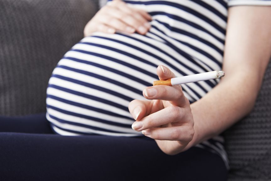 Schwangere auf dem Sofa mit einer Zigarette