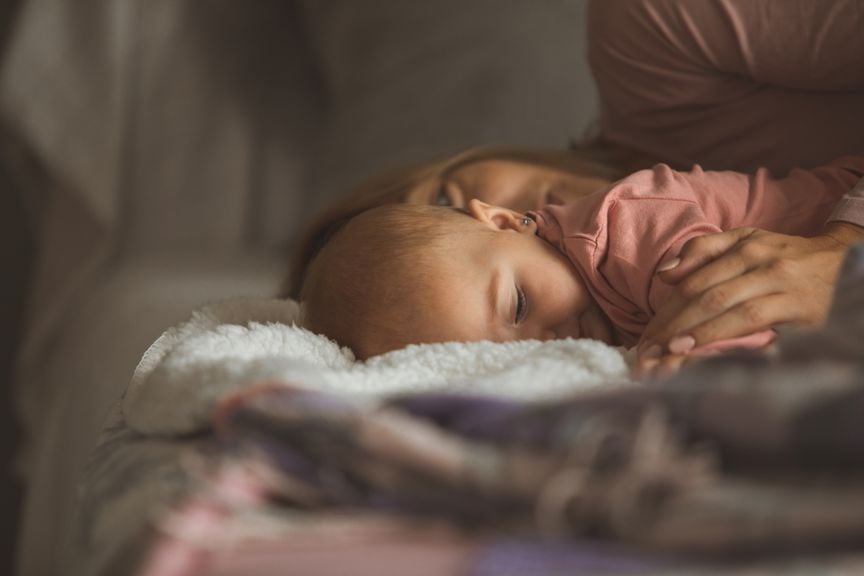 Mutter kuschelt mit Baby im Bett