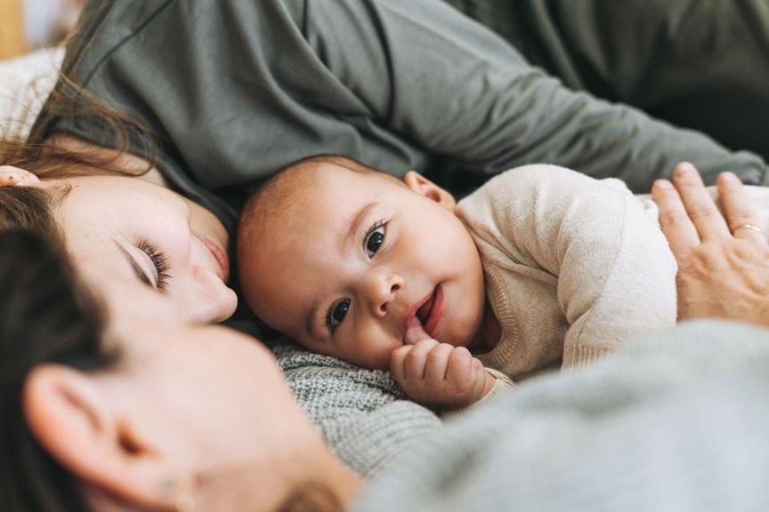 Baby kuschelt mit Eltern im Bett