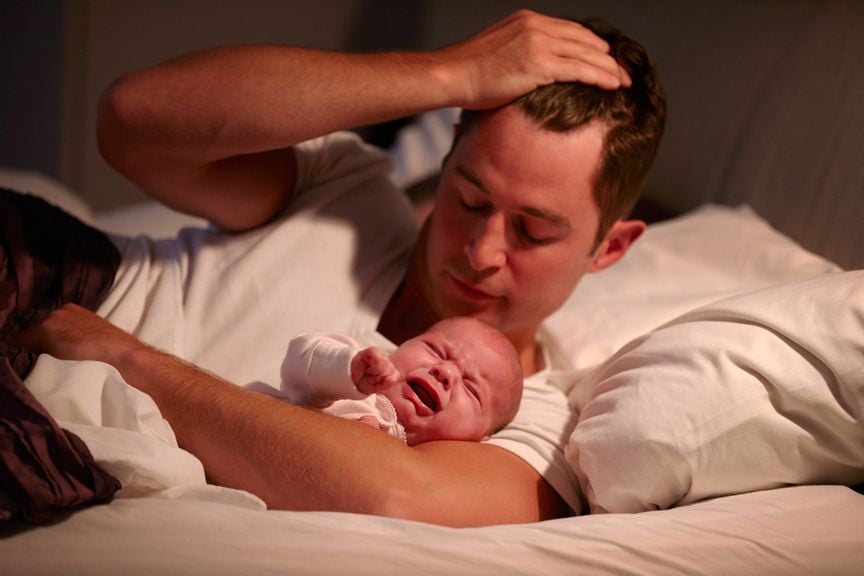 Vater mit schreiendem Baby im Bett