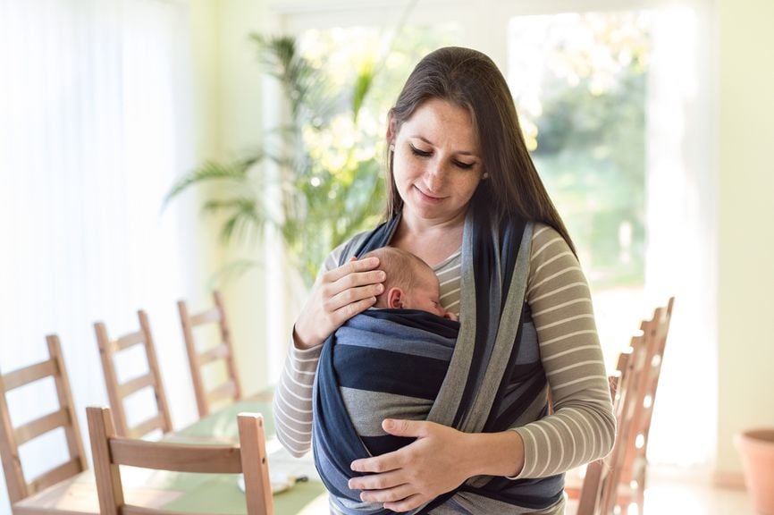 Mutter hält ihr Baby liebevoll im Tragtuch