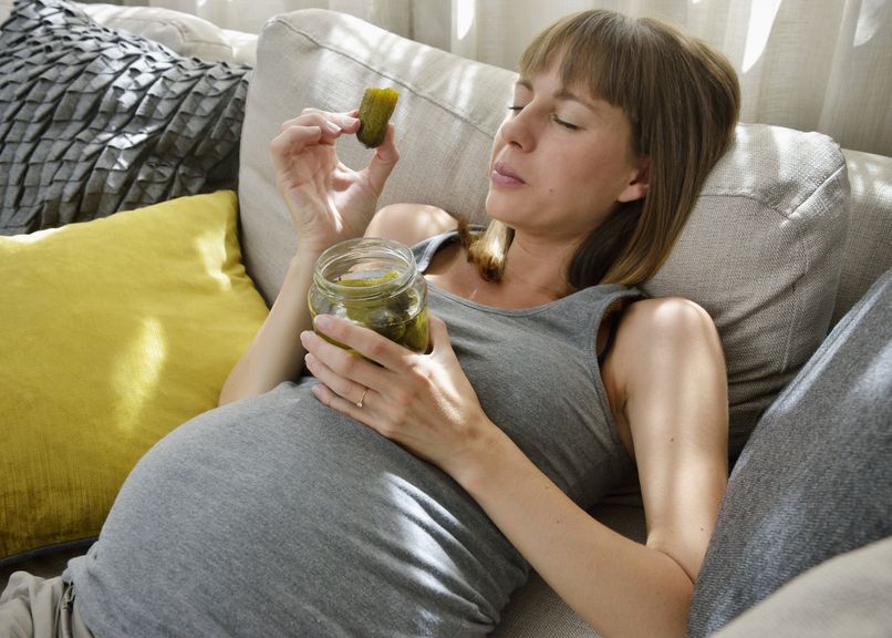 Schwangere isst auf dem Sofa