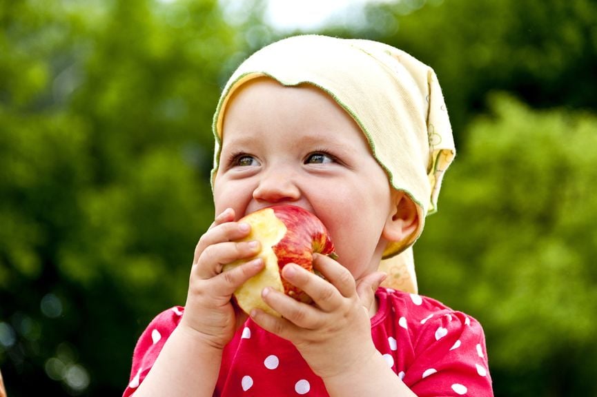 Kind beisst in einen Apfel 