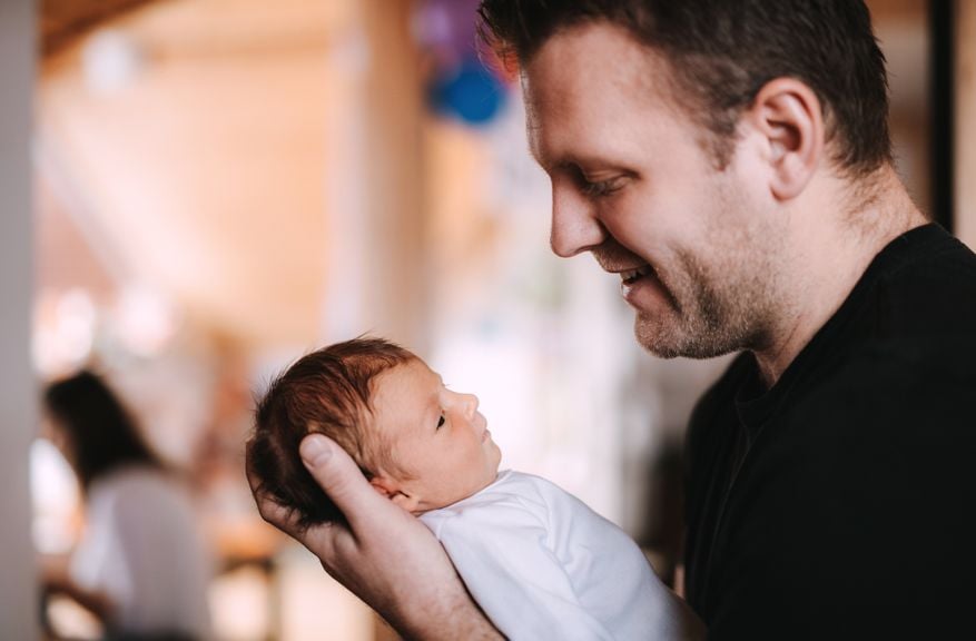 Vater lächelt sein Neugeborenes an