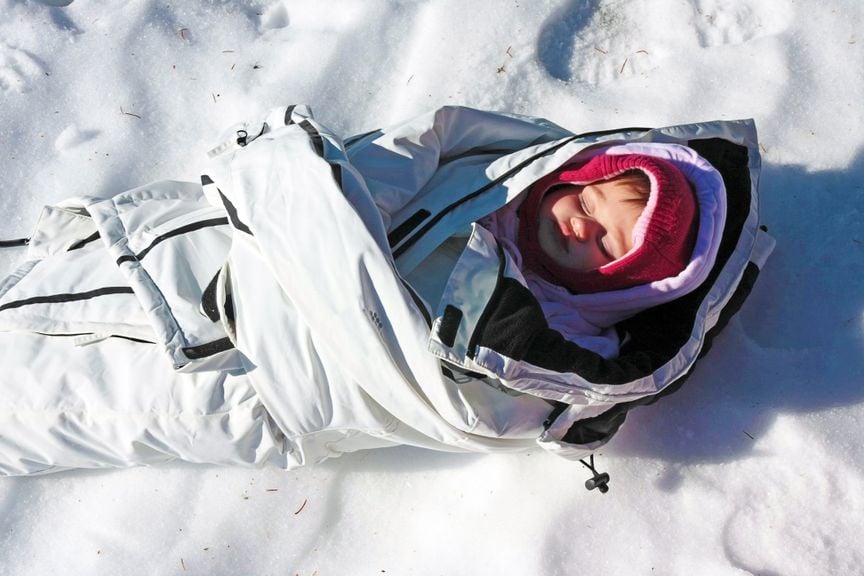 Baby liegt in eine Jacke gewickelt im Schnee