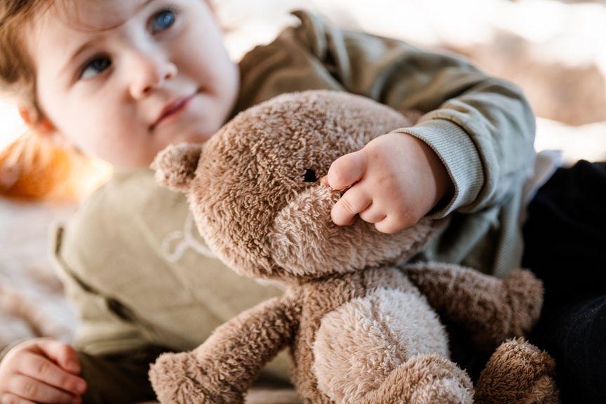 Kleinkind packt seinen Teddy an der Nase