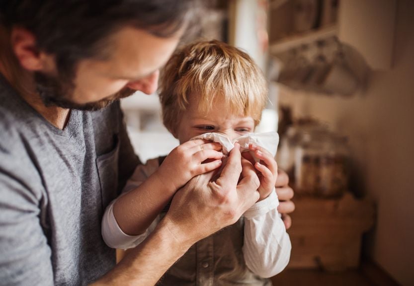 Vater hilft Kind die Nase zu putzen