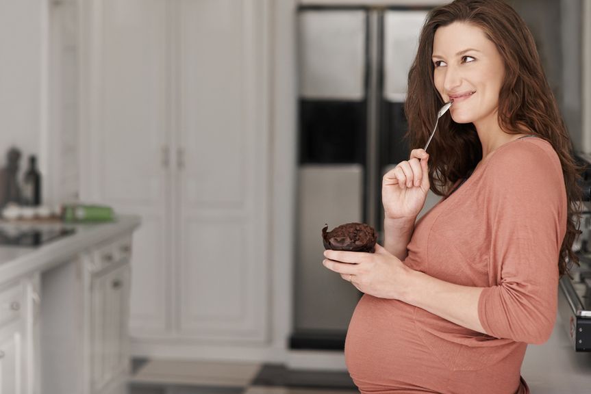 Schwangere isst einen Schokoladenmuffin