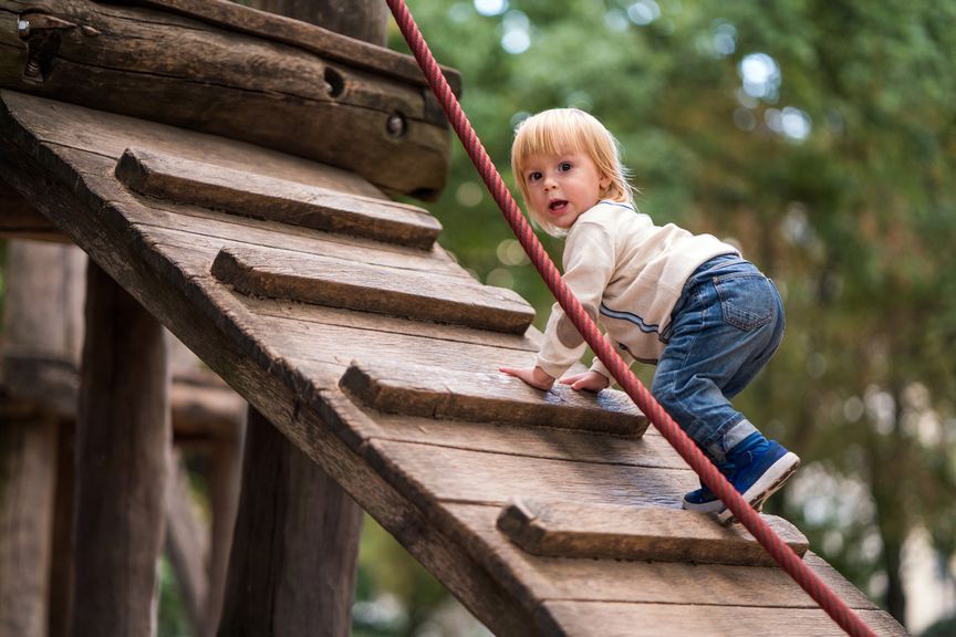 Kind klettert auf dem Spielplatz